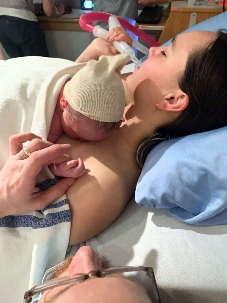 Woman using laughing gas while holding her newborn baby