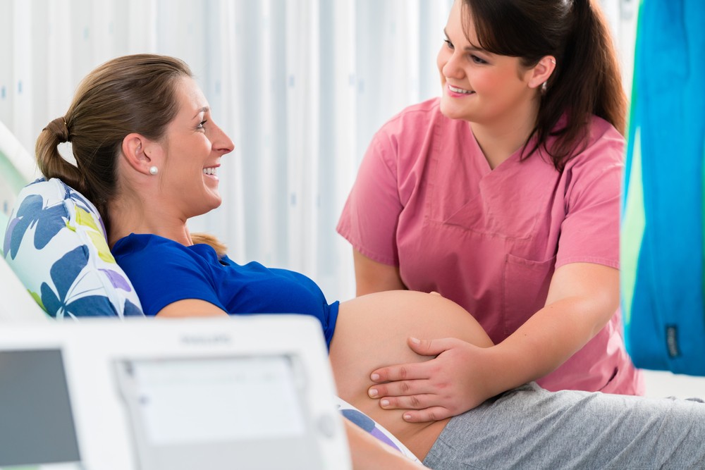 Midwife checking pregnant belly