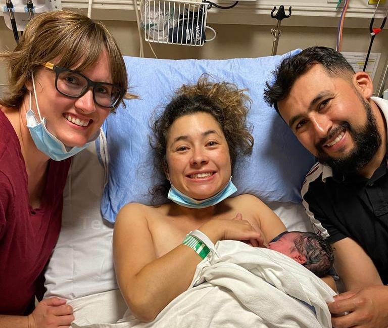 New mother and baby with husband and doula in hospital