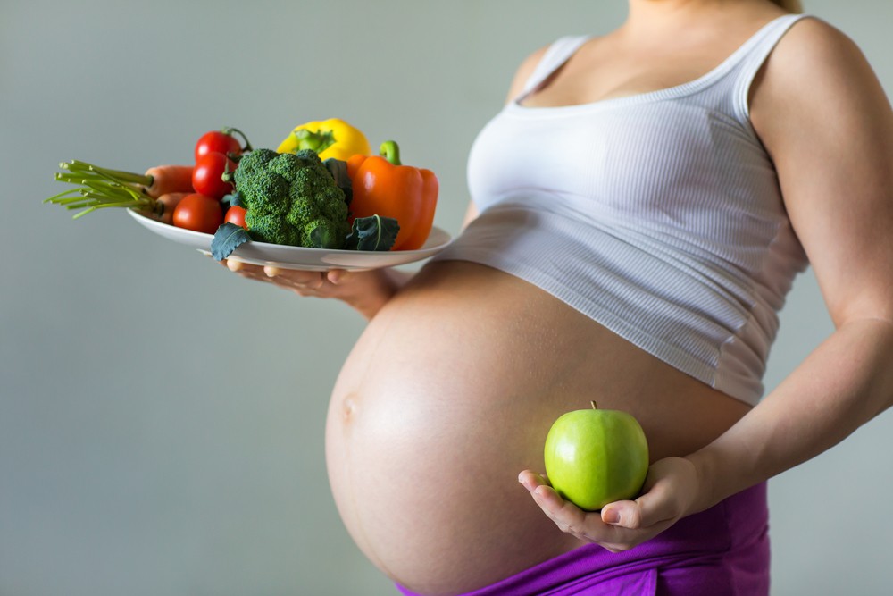 Pregnant woman holding veggies