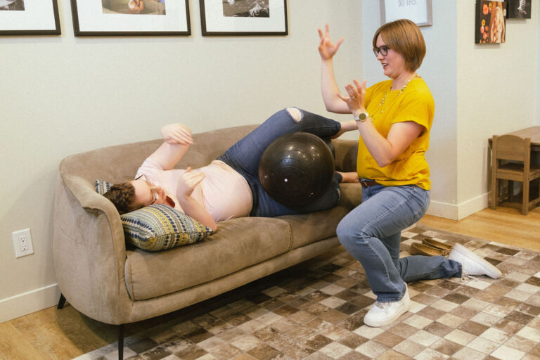 Pregnant woman using birth ball with doula's help