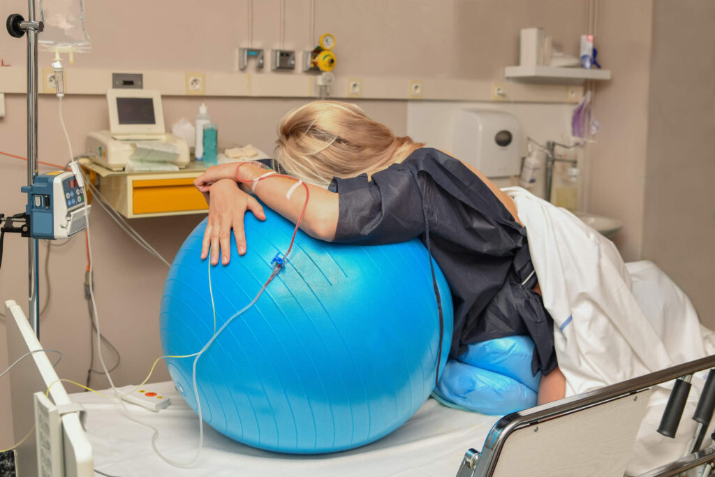 Woman using birth ball in labor in hospital bed