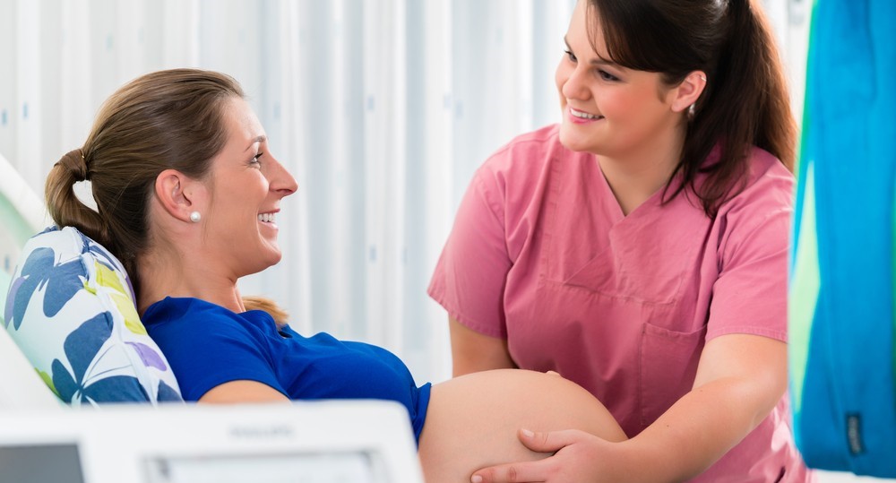 Midwife checking pregnant belly